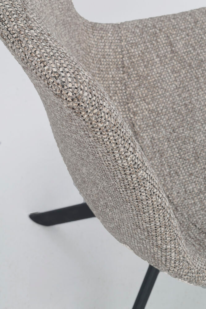 Lähikuvassa Dunmore-tuolin tumman beigeä kangasverhoilua ja alaspäin levittyvät mustat metallijalat.