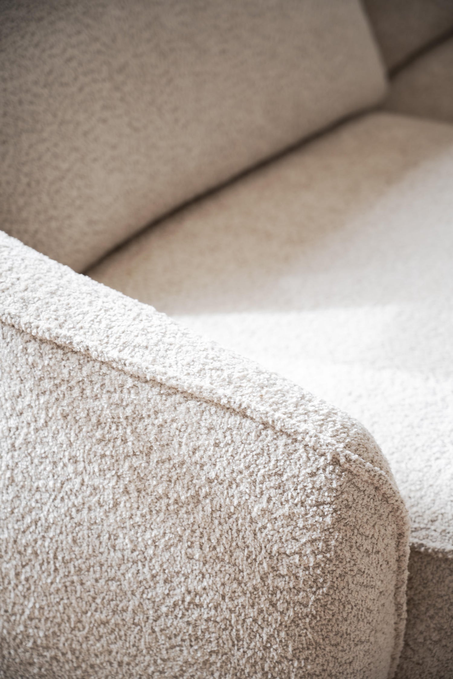 Lähikuvassa Norris-sohvan kaarevaa muotoilua. Verhoiluna vaalea beige Anna 2-kangas.