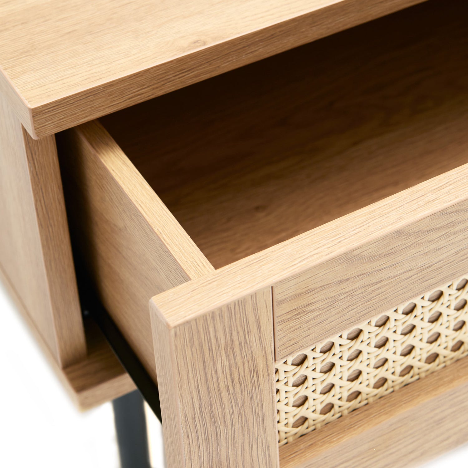 Lähikuvassa Pensacola-sohvapöytä, luonnonvärinen tammi. Sohvapöydän molemminpuolisten laatikoiden etulevyissä on yksityiskohtana polyrottinki. Mustat metallijalat.
