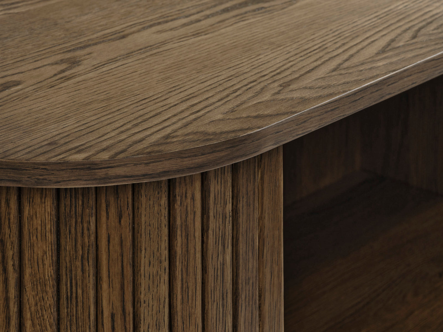 Ovaalinmuotoinen Nola-tv-taso 120 cm, savutammenvärinen. Lähikuvassa kannen pintaa ja liukuoven panelointia.