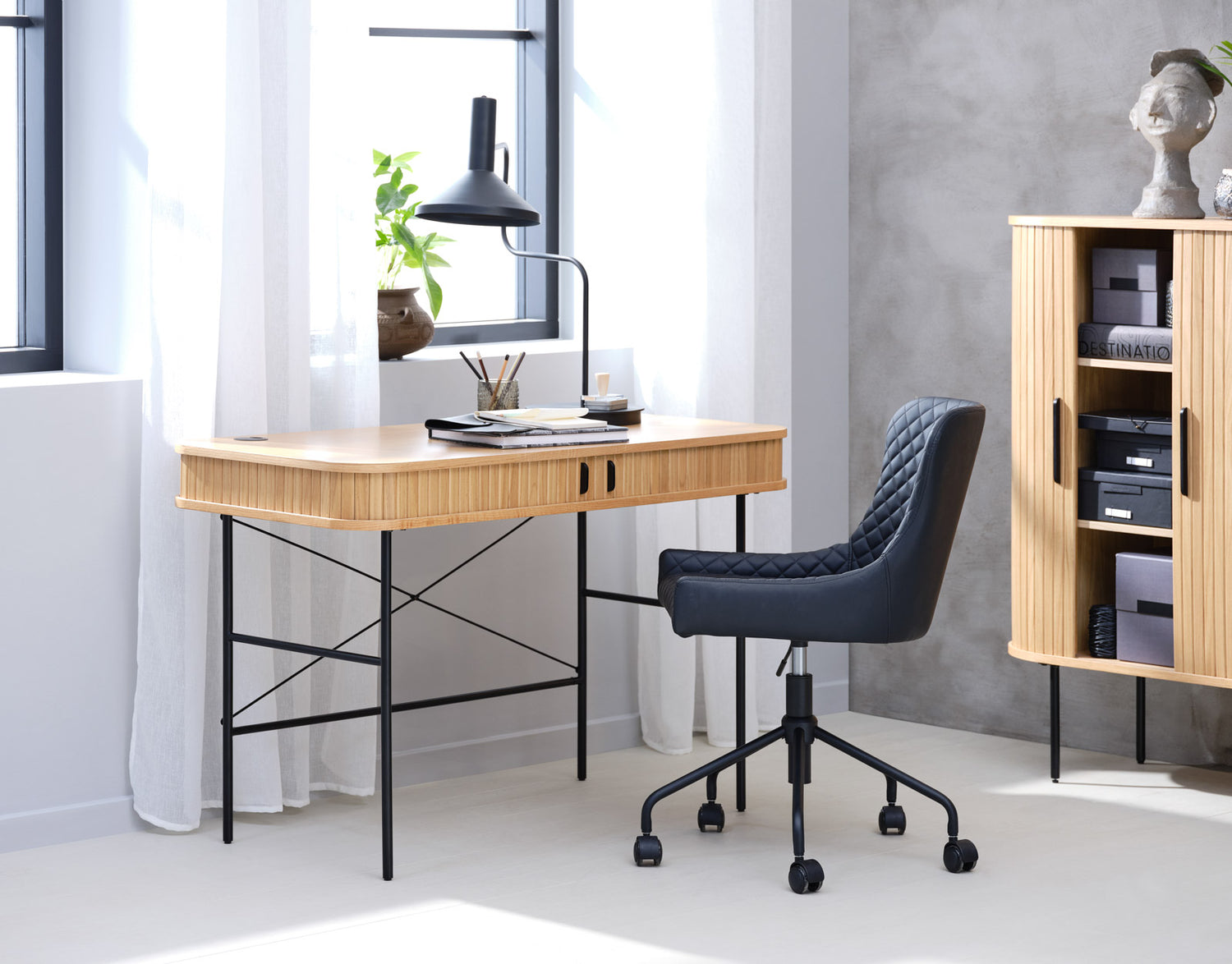 Kuvassa on Nola-työpöytä tammenvärisenä. Sormipaneloiduissa liukuovissa on mustat metalliset vetimet ja mustat metallijalat ovat säädettävät.