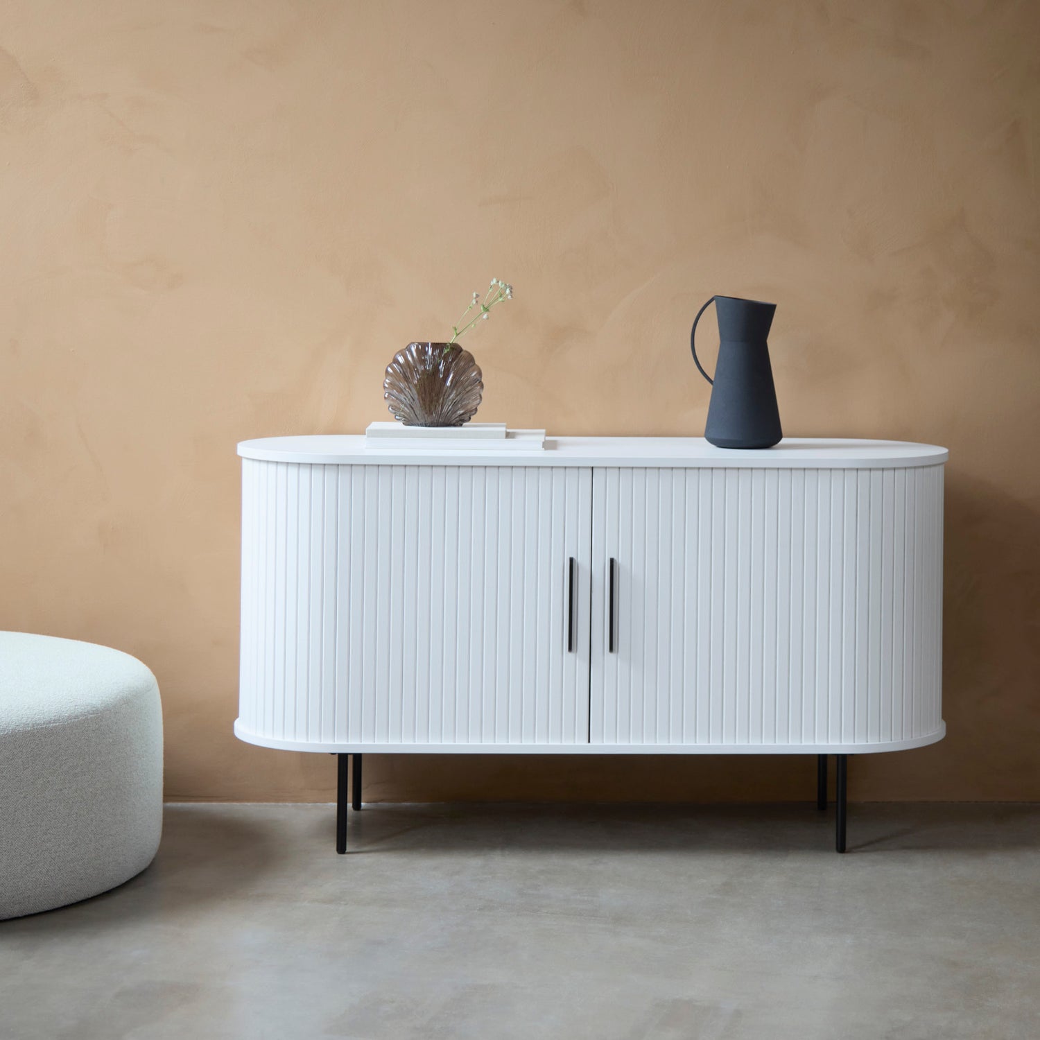 Kuvassa on Nola-senkki, valkoinen. Liukuovissa on mustat metalliset vetimet ja mustat metallijalat ovat säädettävät.