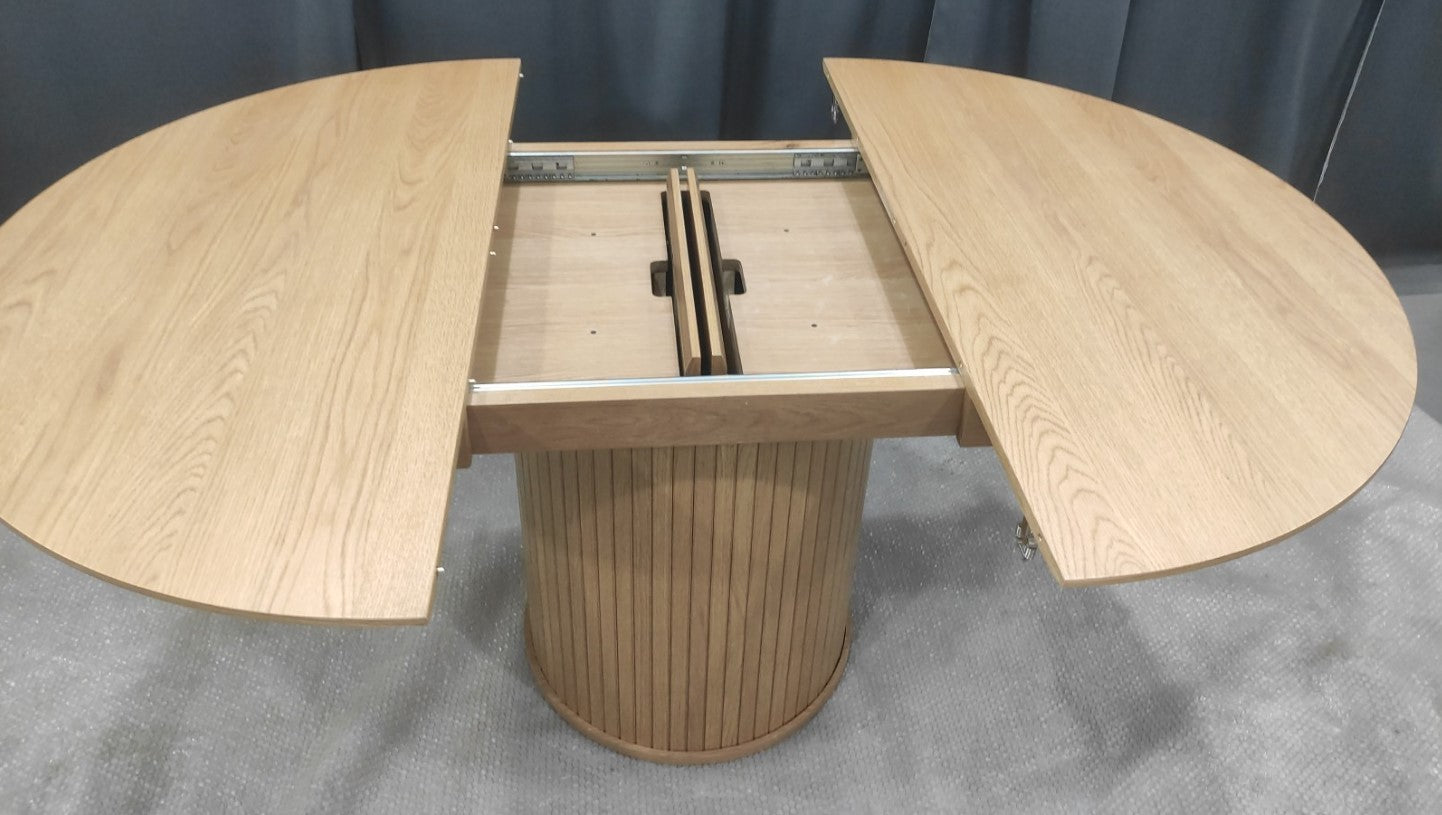 Jatkettava 120 cm Nola-ruokapöytä jatketaan keskeltä pöytää, jossa jatkopaloja säilytetään kannen alla.