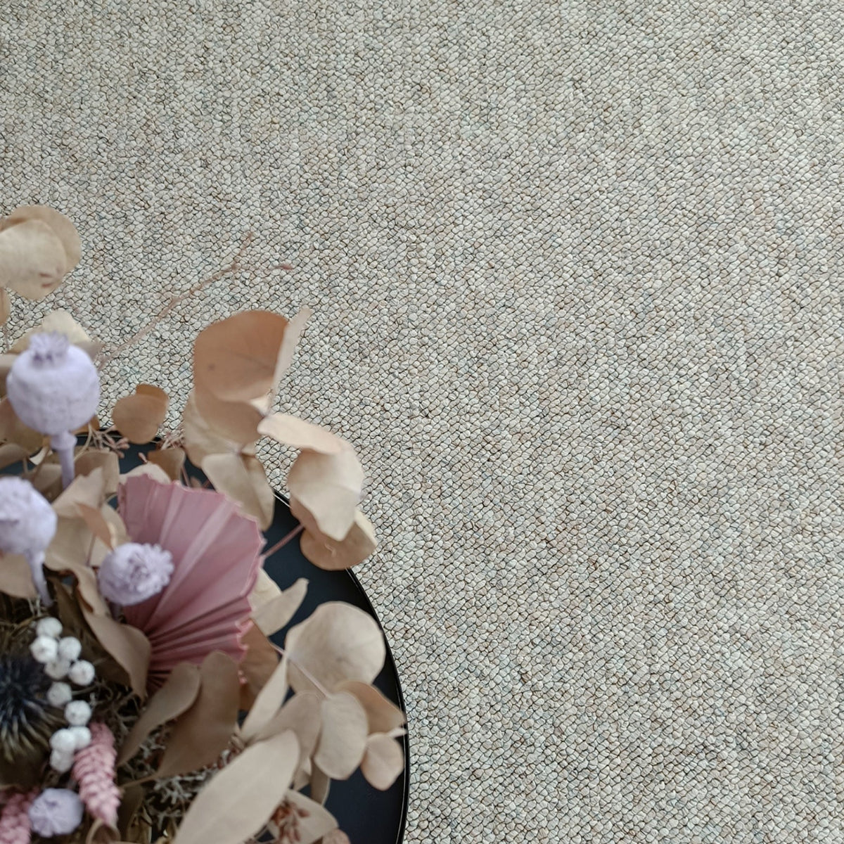 Kuvassa on beige-harmaa sileäpintainen Ahto-matto kuvattuna sohvapöydän alla.