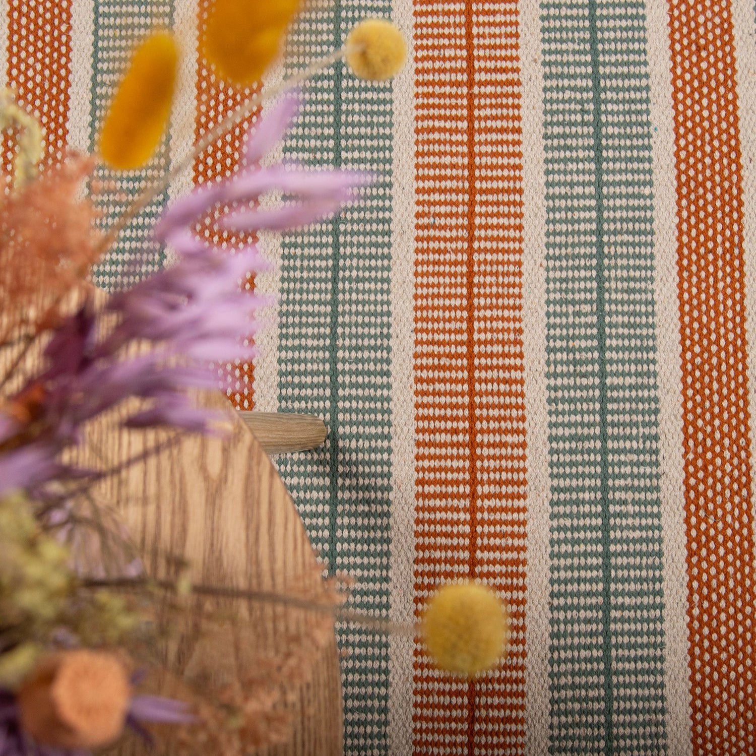 Kuvassa Foksi-puuvillamatto kuvattuna sohvapöydän alla, maton väri terra-vihreä.