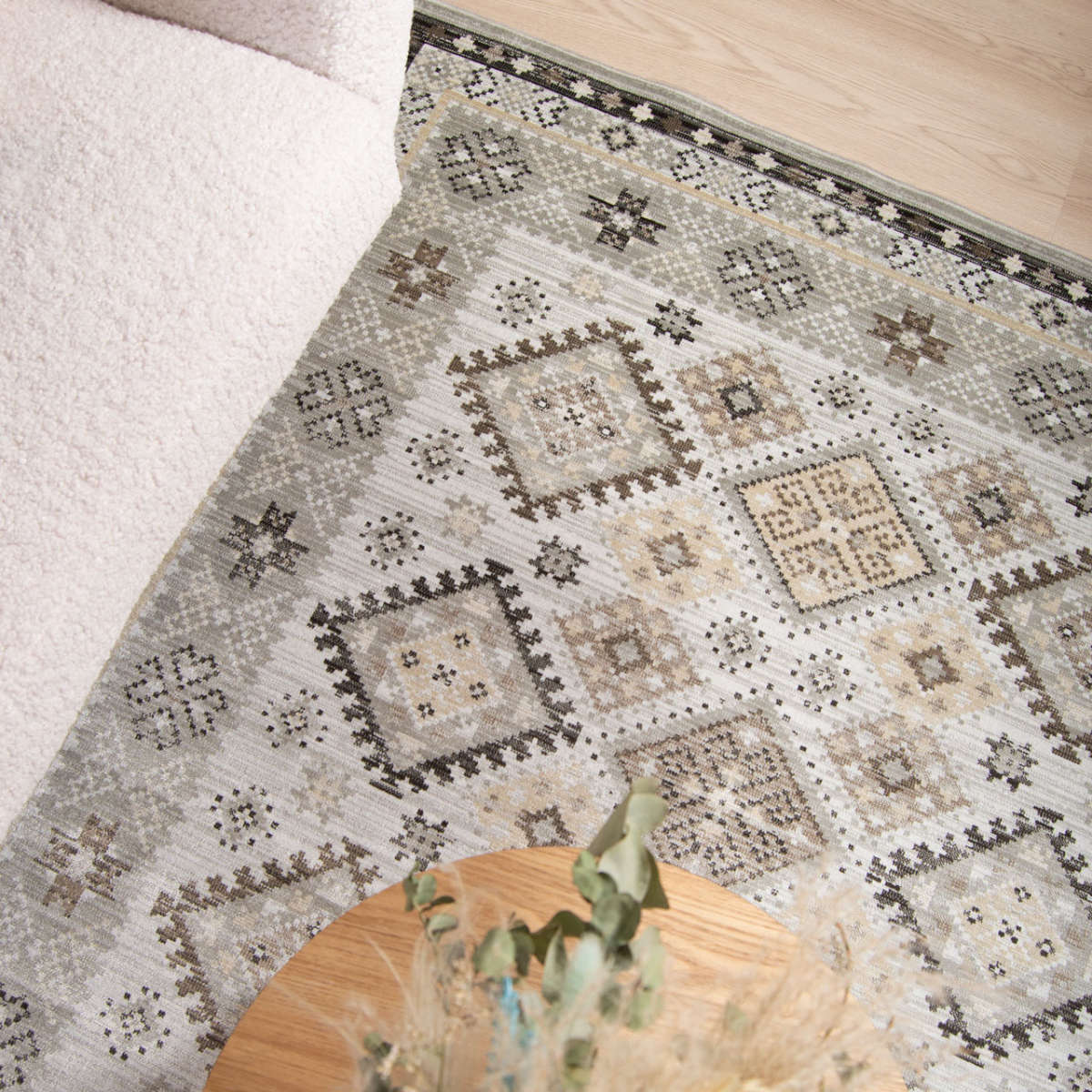 Kuvassa Ismir-viskoosimatto sohvan edessä, sohvapöydän alla kuvattuna. Matossa on luonnolliset sävyt, kuten beige, ruskea ja harmaa.