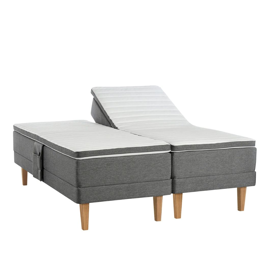 Antrasiitin värinen Aava-moottorisänky Royal-tammijaloilla ja profiloiduilla sijauspatjoilla. Kuvan tarviketasku myydään erikseen.