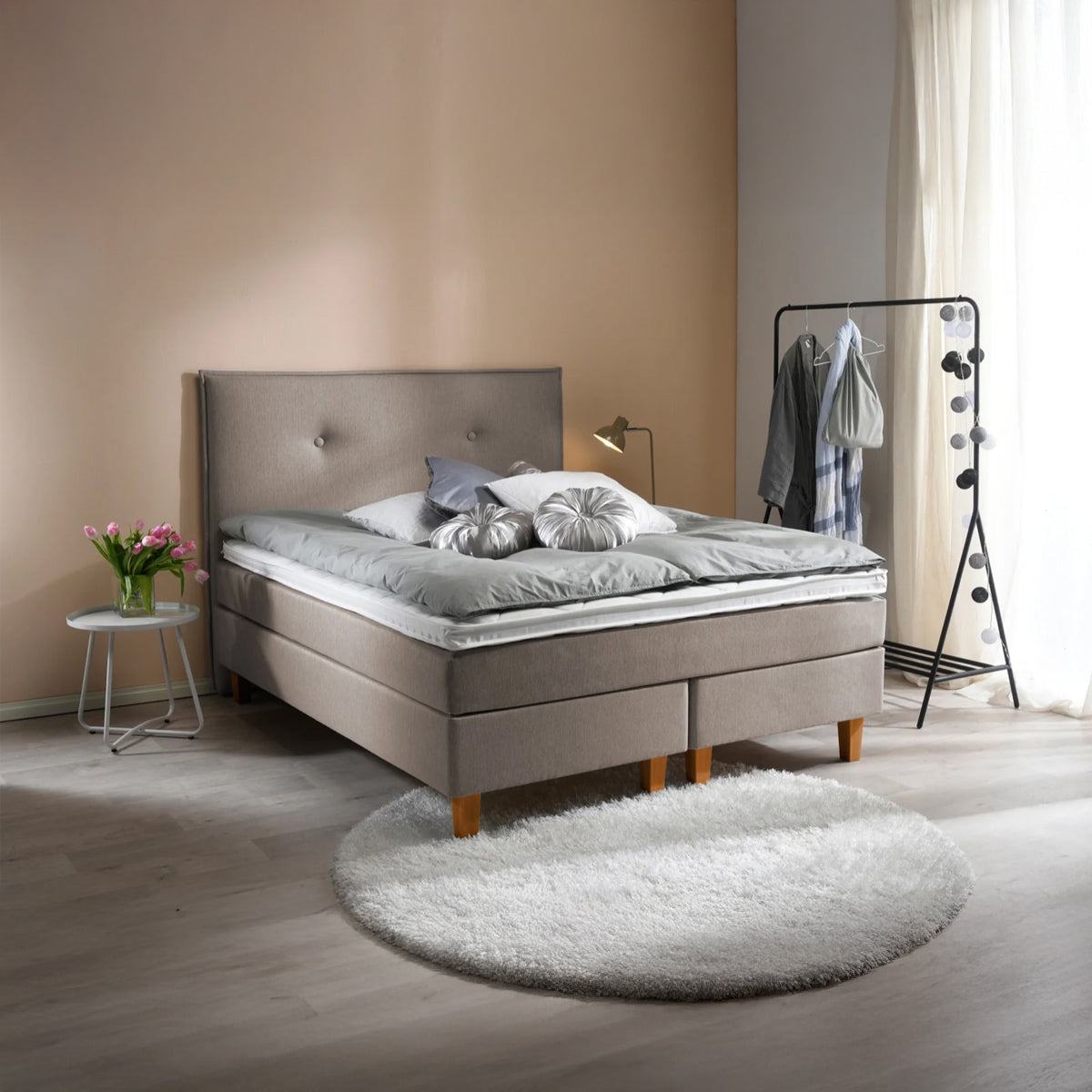 Ranta-jenkkisängyn beige sävy sopii monenlaiseen sisustukseen. Kuvassa beigenvärinen Ranta-jenkkisänky luonnonvärisillä Royal-tammijaloilla ja valkoisella profiloidulla sijauspatjalla. Kuvan sängynpääty myydään erikseen.