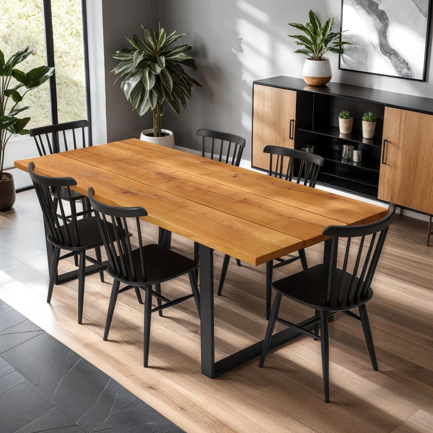 Kuvassa on Rustica-ruokapöytä luonnonvärisellä 3-lankkuisella tammikannella ja mustilla metallijaloilla, sekä mustat Anni-pinnatuolit. Lankkupöydän rustiikkinen kansi on aina yksilöllinen ja lankkujen välissä on raot.