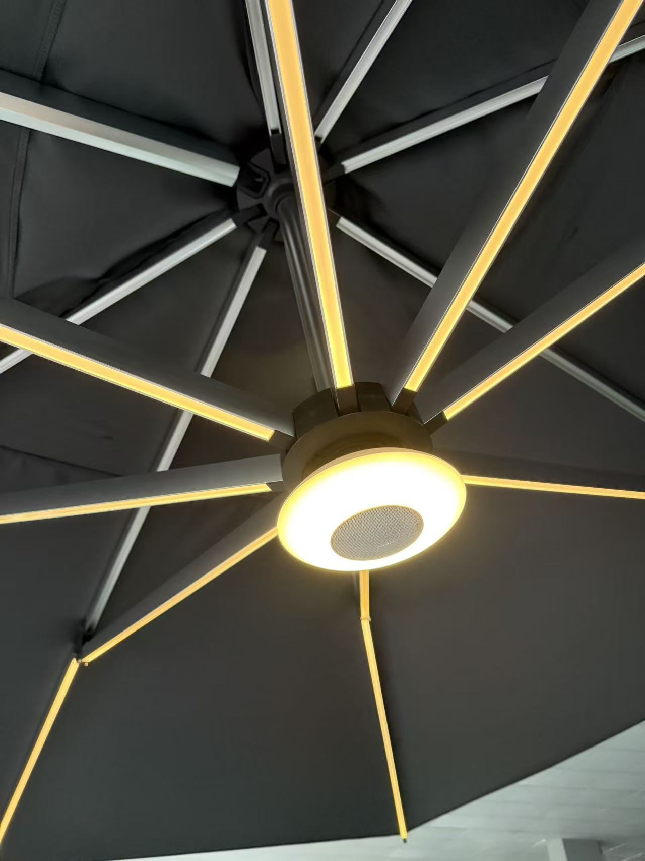 Aurinkovarjon Bluetooth-kaiutin, kuvattuna erikseen myytävän varjon alla/sisäpuolella. Kaiuttimessa on myös säädettävä LED-valo.