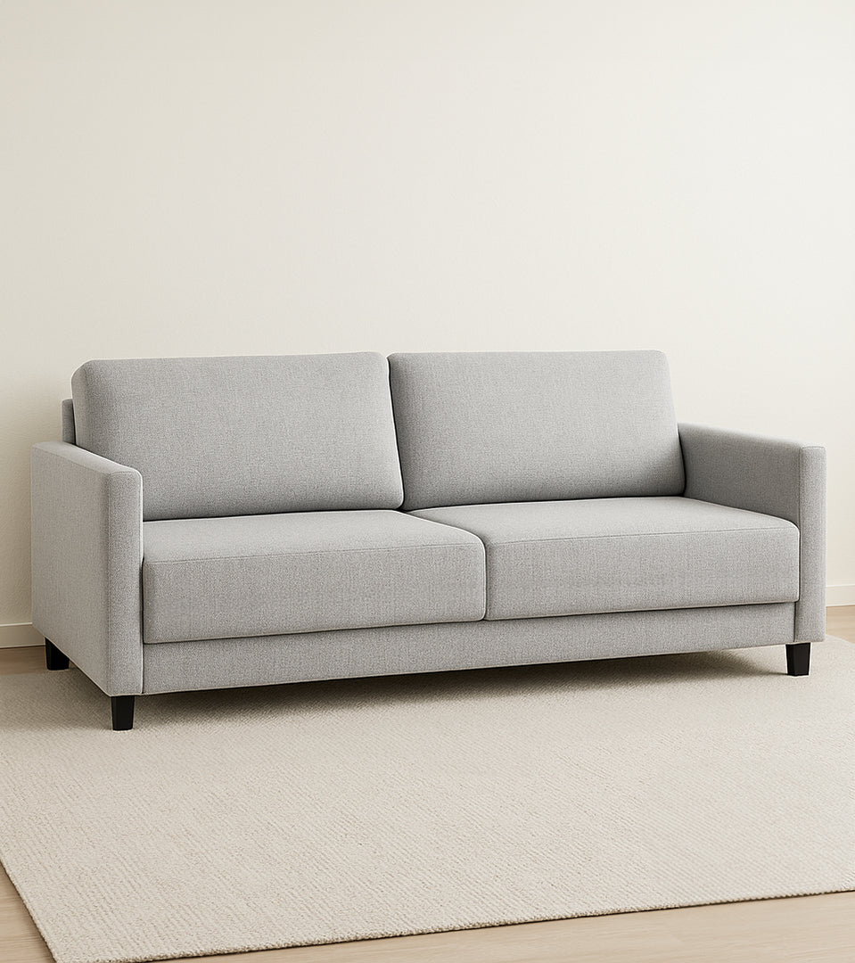 Lilja-vuodesohva vaaleanharmaalla Verde 18 -kankaalla ja 10 cm korkeilla mustilla puujaloilla. Tyylikäs sohva kätkee sisäänsä erittäin helppokäyttöisen vuodemekanismin. Stailattu visualistointi.