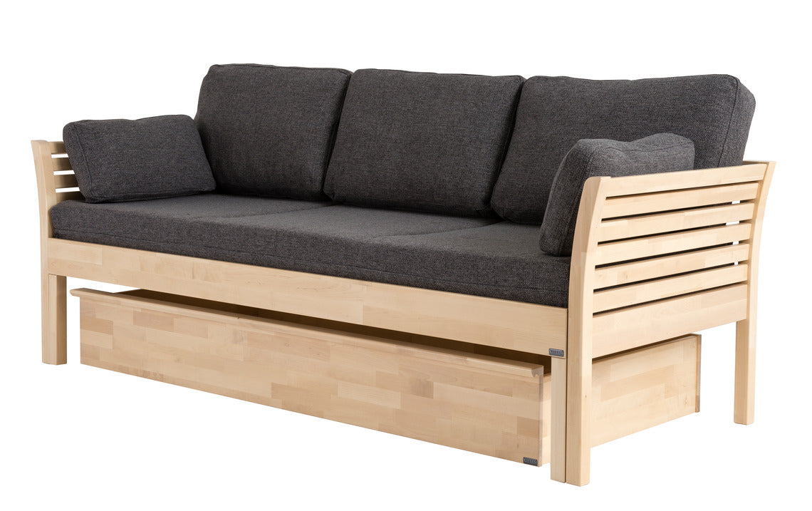 Koivunvärinen Kanerva-puusohva harmaalla Levon-taittopatjasarjalla. Patjasarja ja Kanerva-vuodevaatelaatikko myydään erikseen.