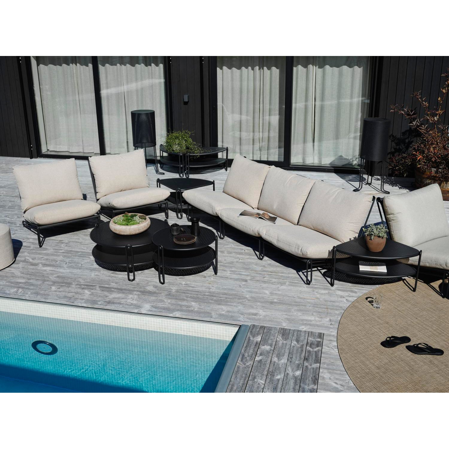 Kuvassa vasemmalla on tämä isompi Ø 85 cm musta Blixt-sohvapöytä, joka on 39 cm korkea. Vieressä oikealla on erikseen myytävä 3 cm korkeampi Ø 65 cm limittäin menevä pöytä ja sohvan päädyissä saman sarjan kulmapöydät. Kulmapöydistä on koottu puoliympyrä sohvapöytä myös ikkunoiden väliin.