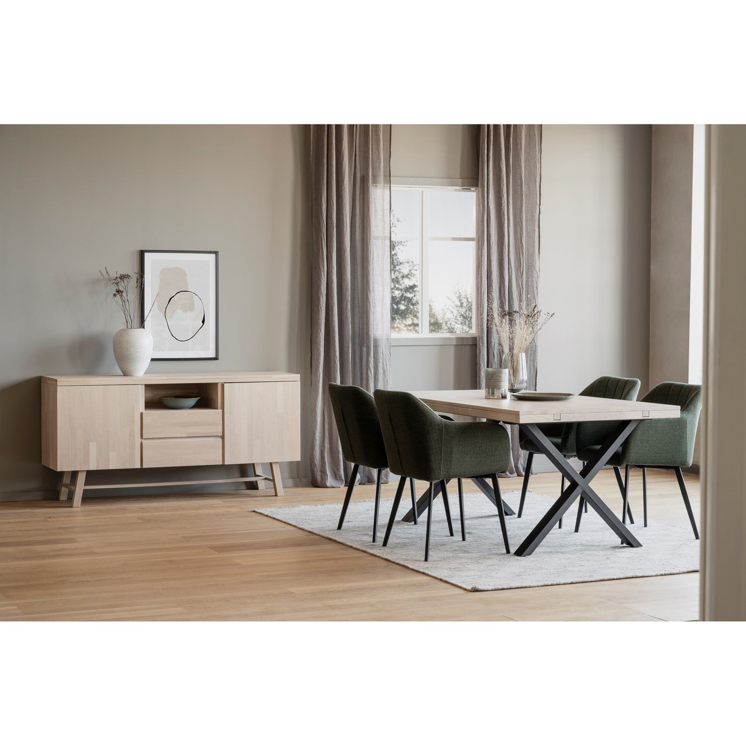 Kuvassa on valkotammenvärinen ruokaryhmä 170 x 95 cm Brooklyn-ruokapöydällä, jossa on X-malliset mustat metallijalat. Neljän hengen ruokaryhmän tuoleina on erikseen myytävät Rowicon vihreät Bolton -tuolit.