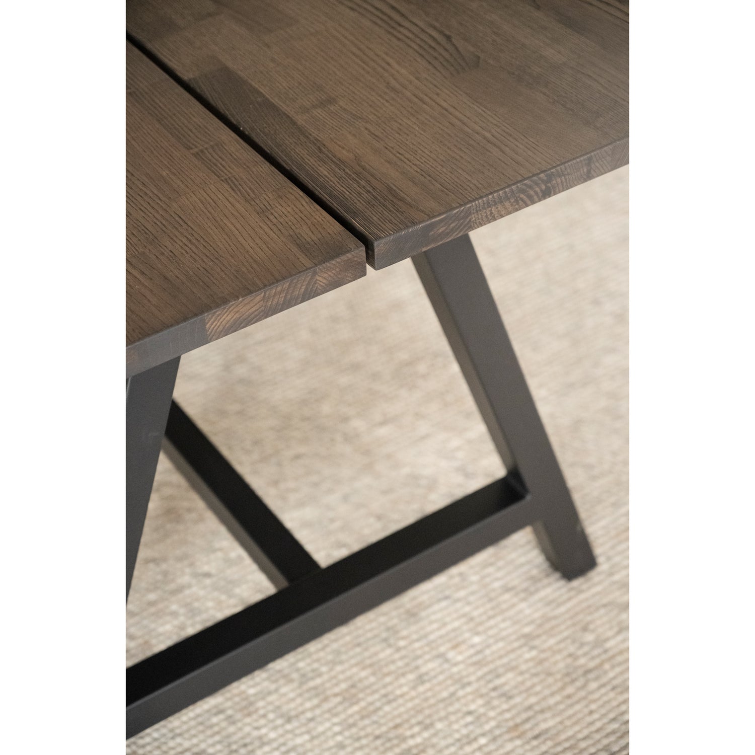 Kuvassa on Carradale-ruokapöydän savutammenvärinen kansi, jonka keskellä on lankkujen välinen rako. Pöydässä on mustat metallijalat.