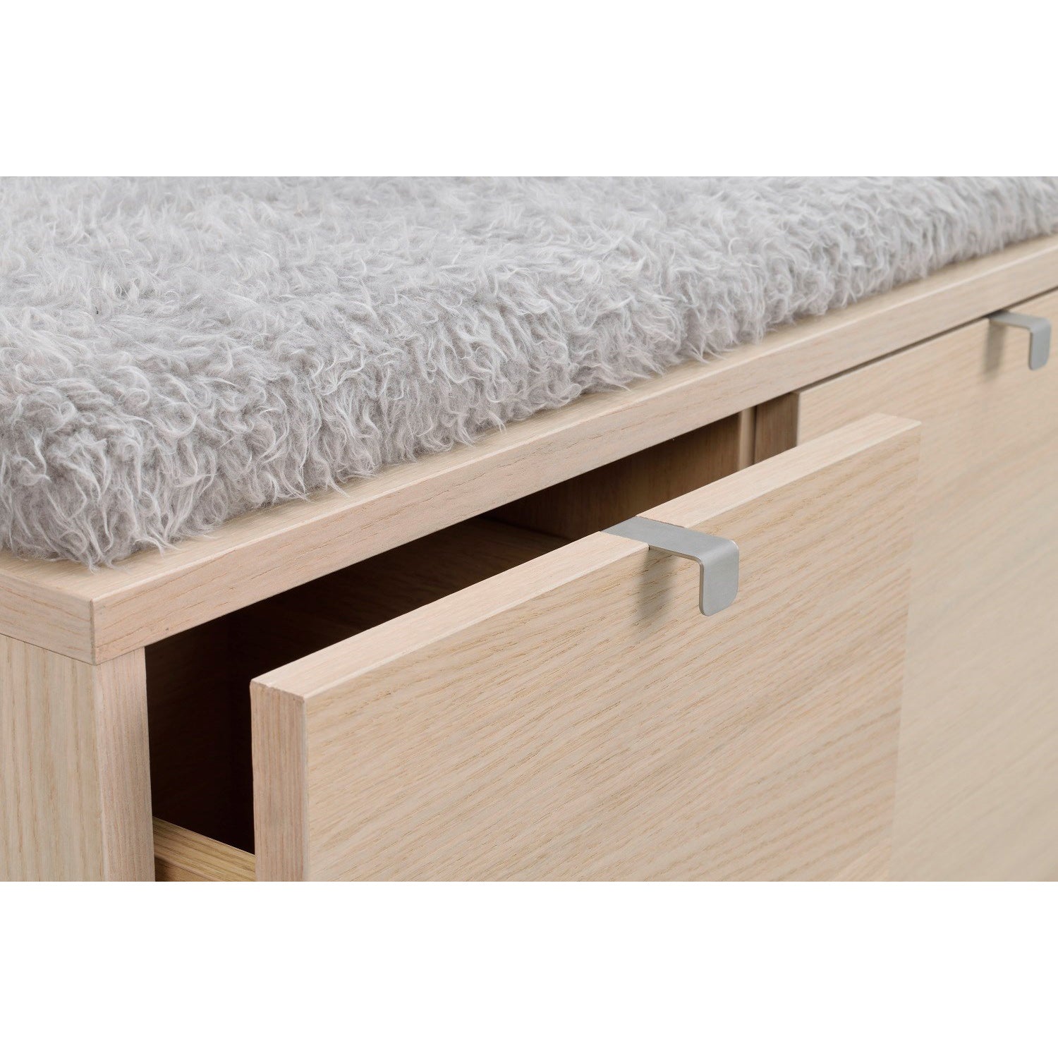 Lähikuvassa valkotammenvärinen Confetti -säilytyspenkki 3-ltk, harmaalla istuinpehmusteella. Laatikoissa on metallivetimet.