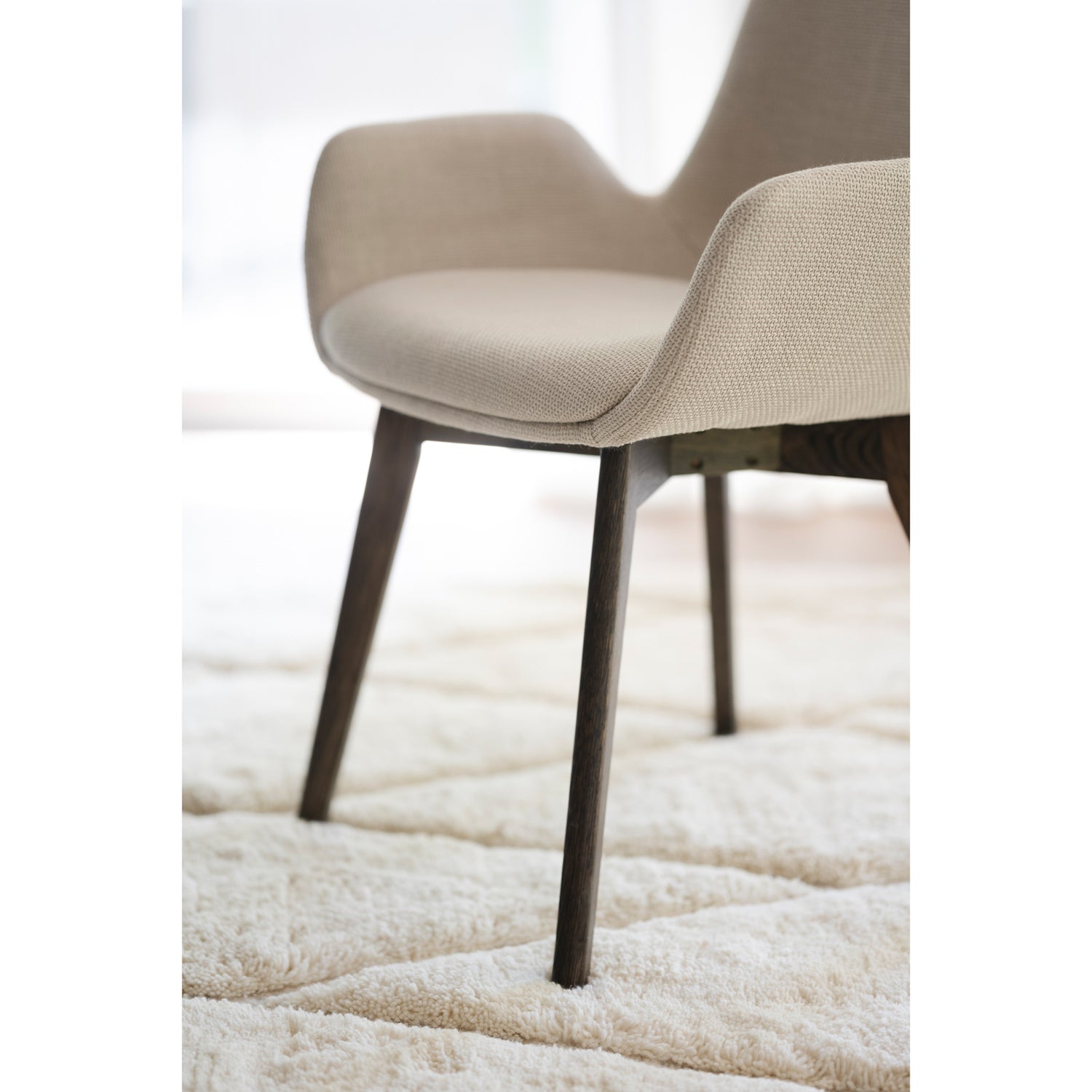 Lähikuva Drimsdale-tuolin beigestä verhoilukankaasta ja ruskeista/savutammenvärisistä jaloista.