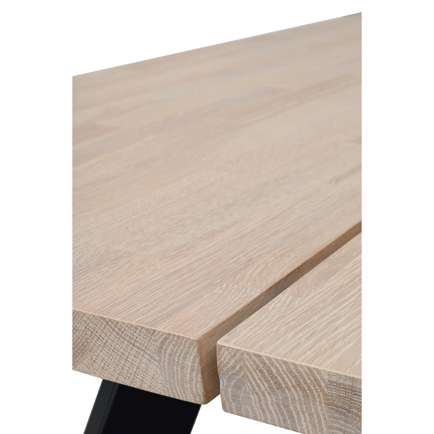 Lähikuvassa Fred-ruokapöydän valkotammenvärinen kannen pinta ja lankkujen välinen rako. Pöydässä on mustat metallijalat.