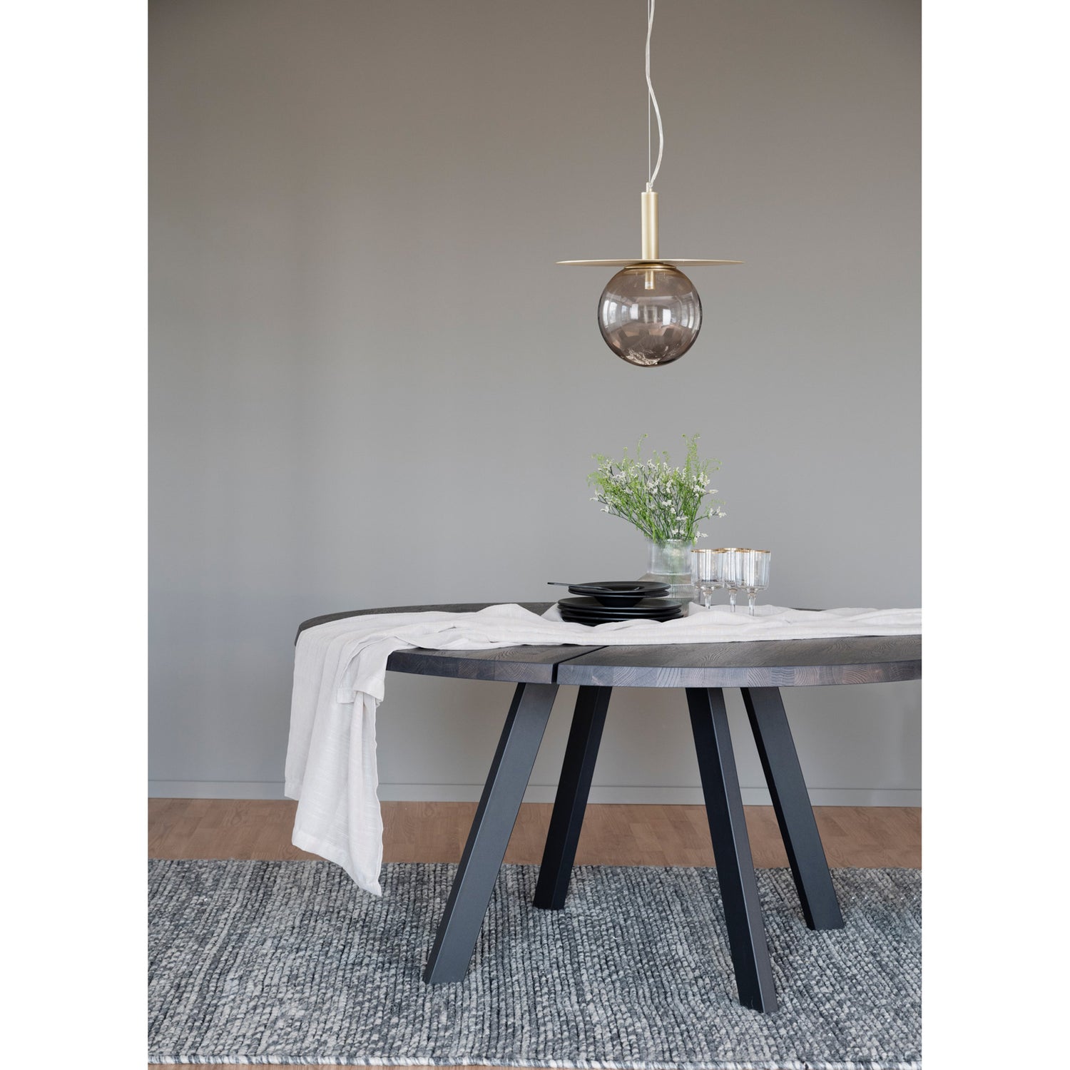 Pyöreä Fred-ruokapöytä savutammenvärisellä kansilevyllä ja mustilla metallijaloilla.