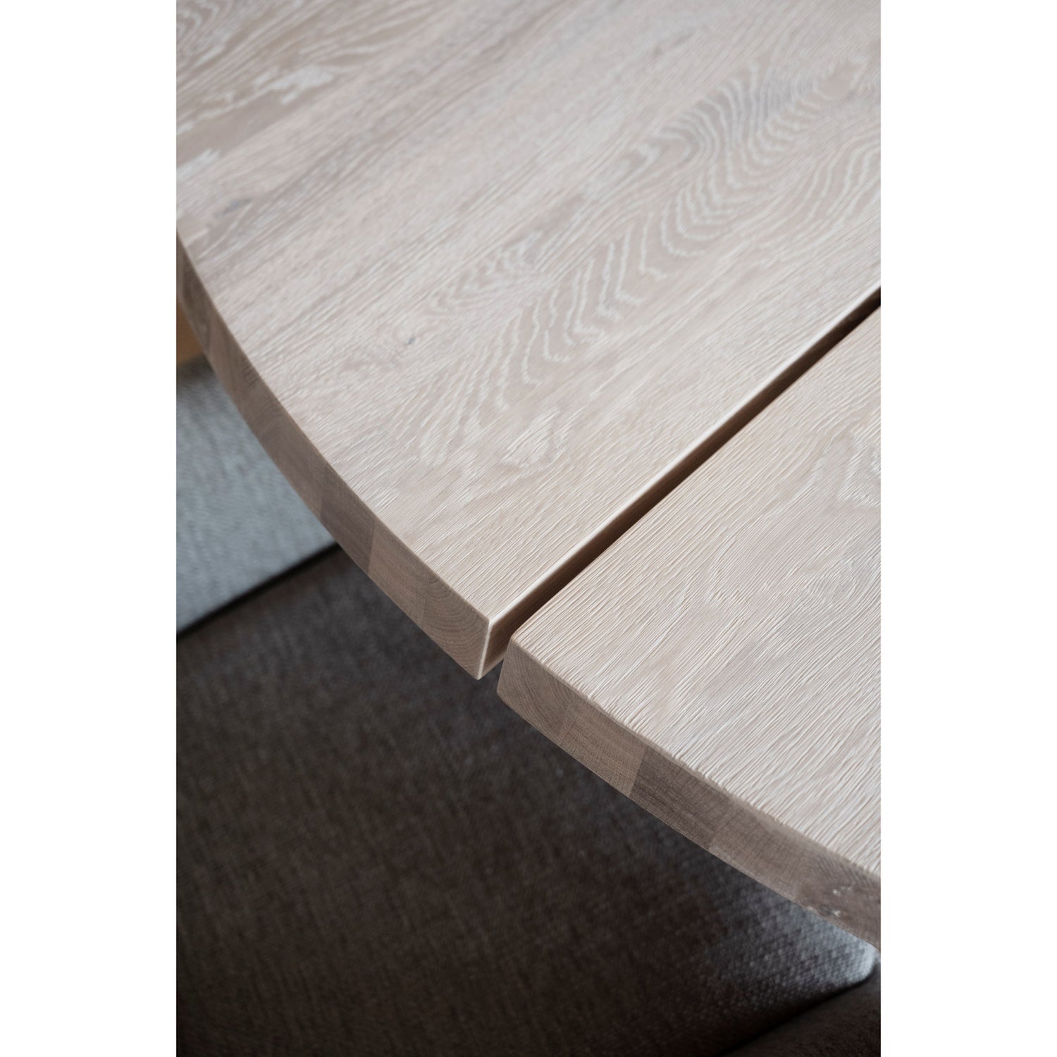 Lähikuvassa valkotammenvärisen pyöreän Fred-ruokapöydän pinta ja lankkujen väliin jäävä rako.