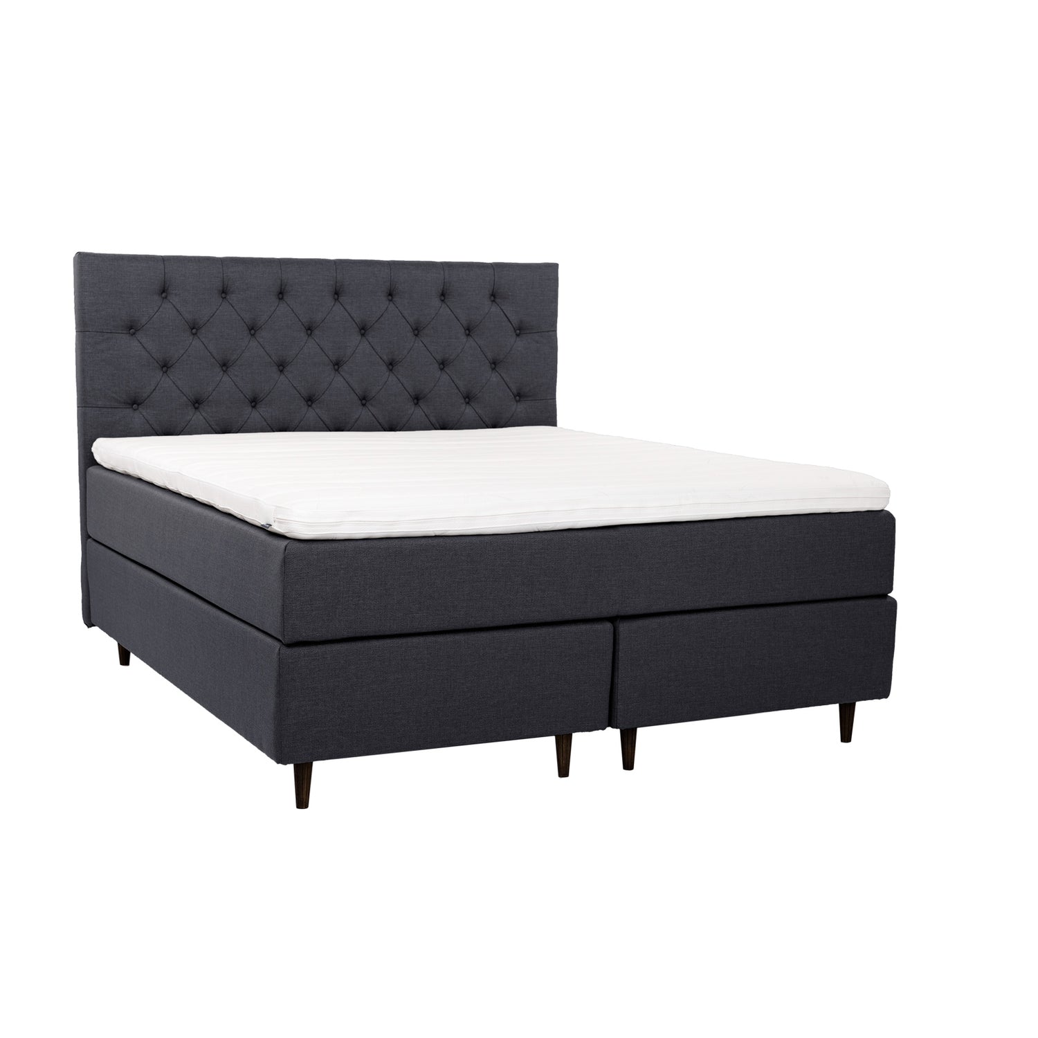 Antrasiitinvärinen Hilding Cross -jenkkisänky tummanruskeilla pyöreillä Hilding Raita -tammijaloilla ja yhtenäisellä Ergo -sijauspatjalla. Kuvan Cross -sängynpääty myydään erikseen.