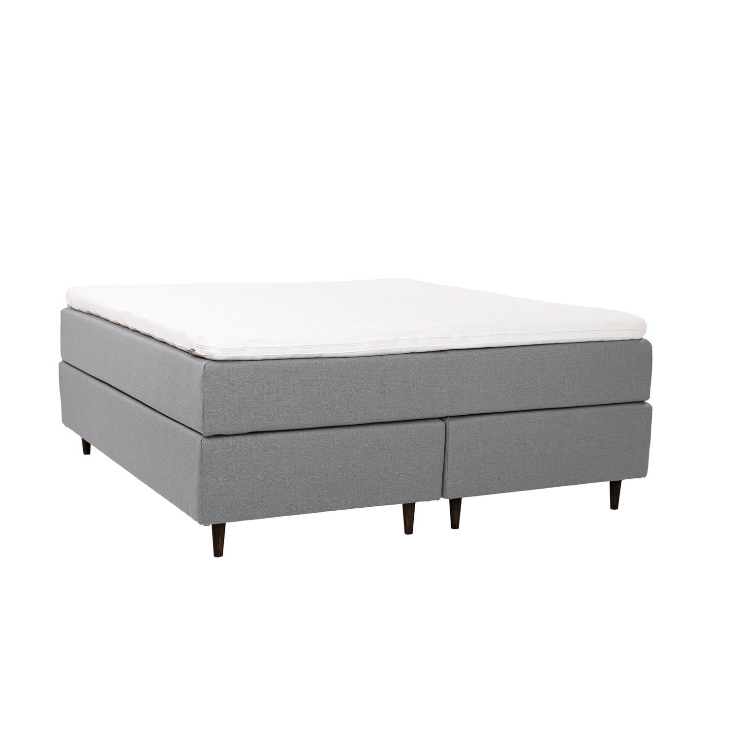 Harmaa Hilding Cross -jenkkisänky tummanruskeilla pyöreillä Hilding Raita -tammijaloilla ja yhtenäisellä Ergo -sijauspatjalla.