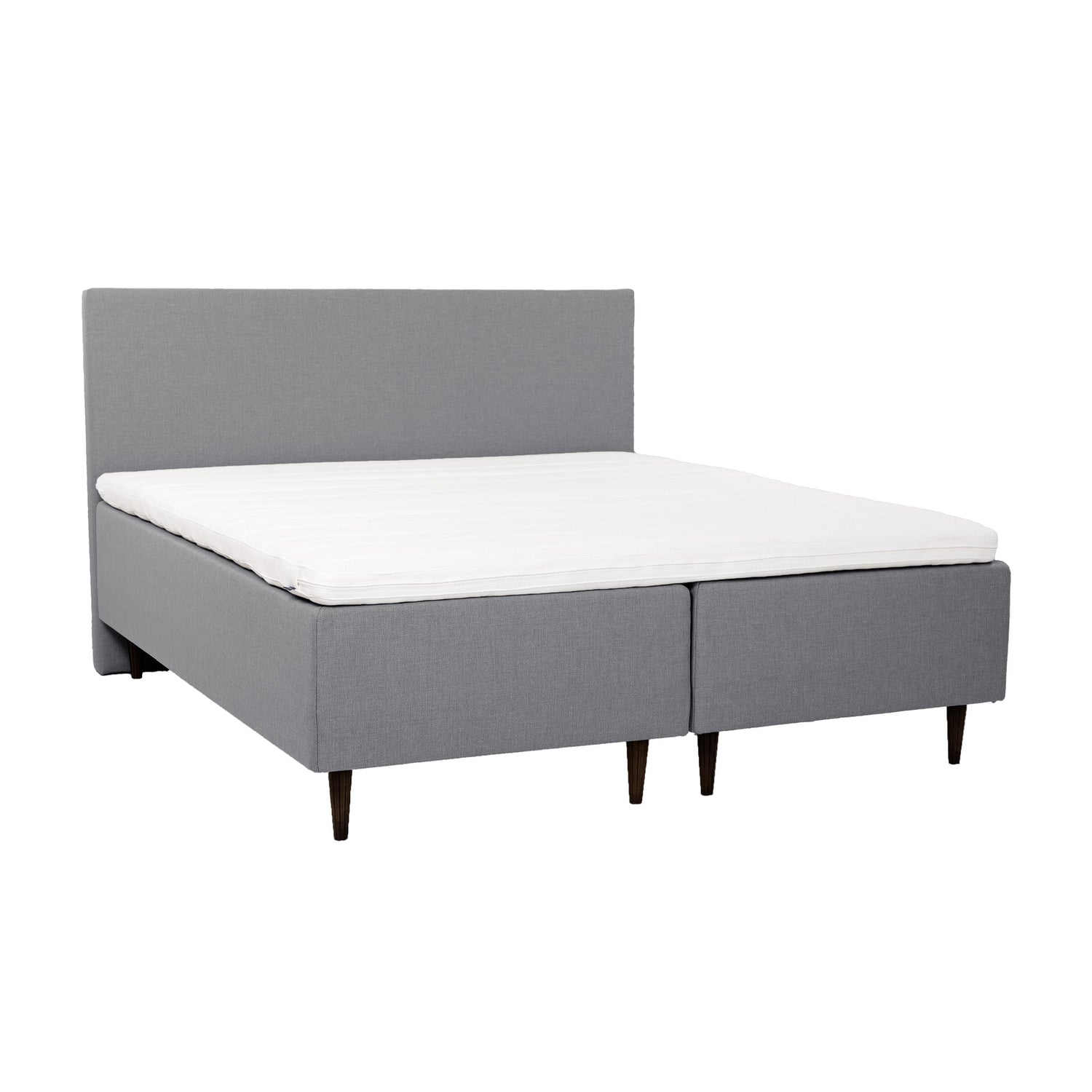 Harmaat Hilding Cross -runkopatjat 90 x 200 cm tummanruskeilla 23 cm korkeilla Hilding Raita -tammijaloilla ja yhtenäisellä Hilding Ergo -sijauspatjalla. Kuvan Original -sängynpääty myydään erikseen.