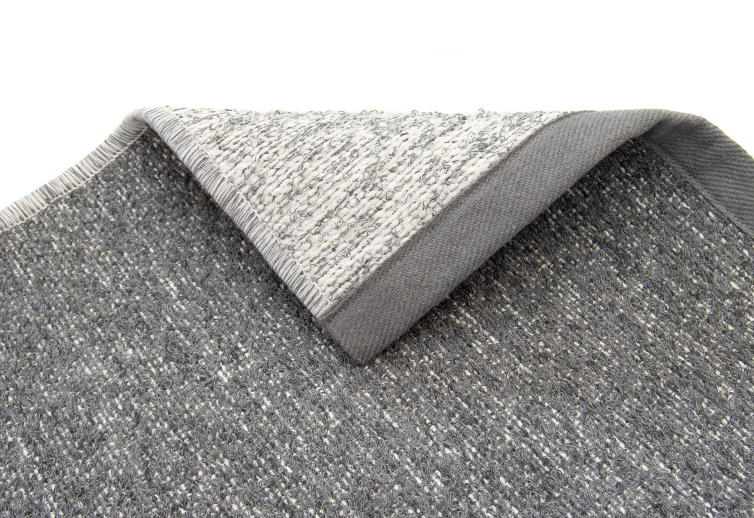 Saima-puuvillamatto on kaksipuoleinen. Lähikuva harmaan maton kääntöpuolesta.