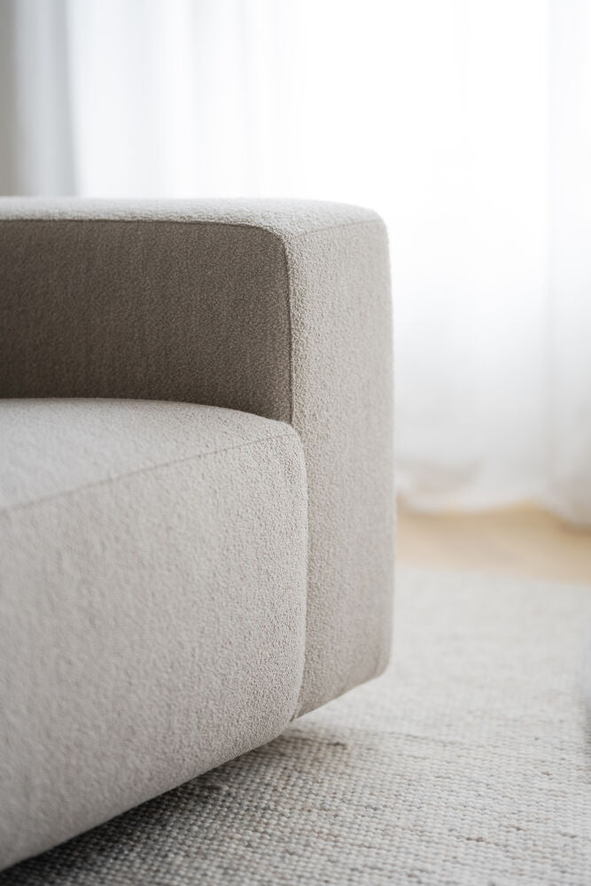 Lähikuvassa on Willard-kulmasohvan vaalean beige Alice 01 -kangasverhoilu ja mustat matalat jalat.