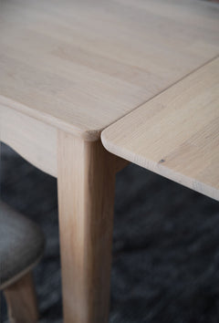 Lähikuvassa näkyy valkotammenvärisen Markham-ruokapöydän jatkolevy kiinnitettynä.