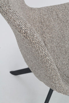 Lähikuvassa Dunmore-tuolin tumman beigeä kangasverhoilua ja alaspäin levittyvät mustat metallijalat.