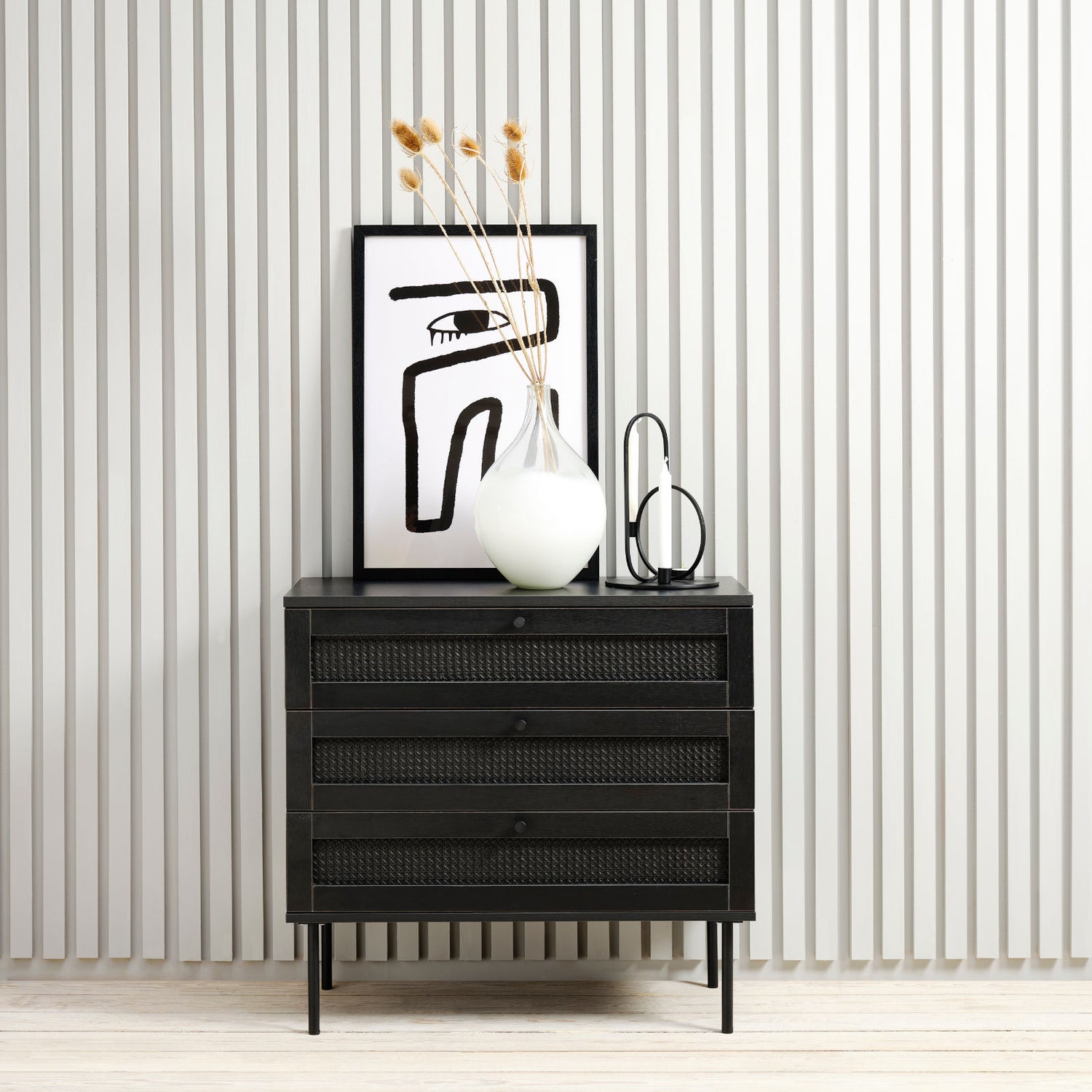 Kuvassa on Pensacola-laatikosto, musta. 3-laatikkoisen lipaston laatikoiden etulevyissä on yksityiskohtana polyrottinki. Mustat metallijalat.