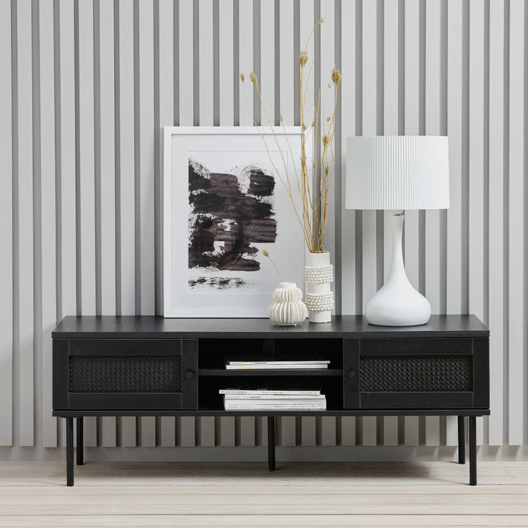 Kuvassa on Pensacola-tv-taso, musta. Tason ovissa on yksityiskohtana polyrottinki. Mustat metallijalat.