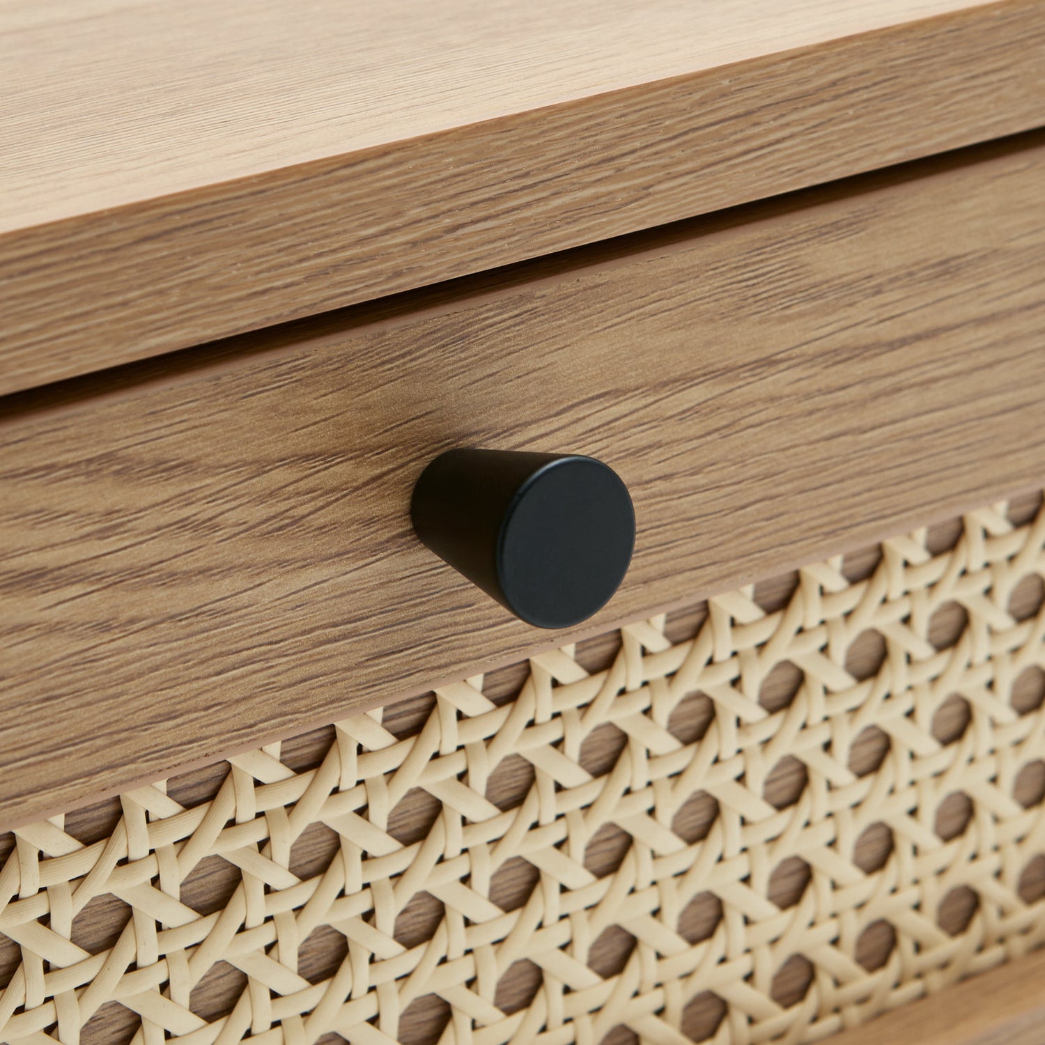 Lähikuvassa Pensacola-sohvapöytä, luonnonvärinen tammi. Sohvapöydän molemminpuolisten laatikoiden etulevyissä on yksityiskohtana polyrottinki. Mustat metallijalat.