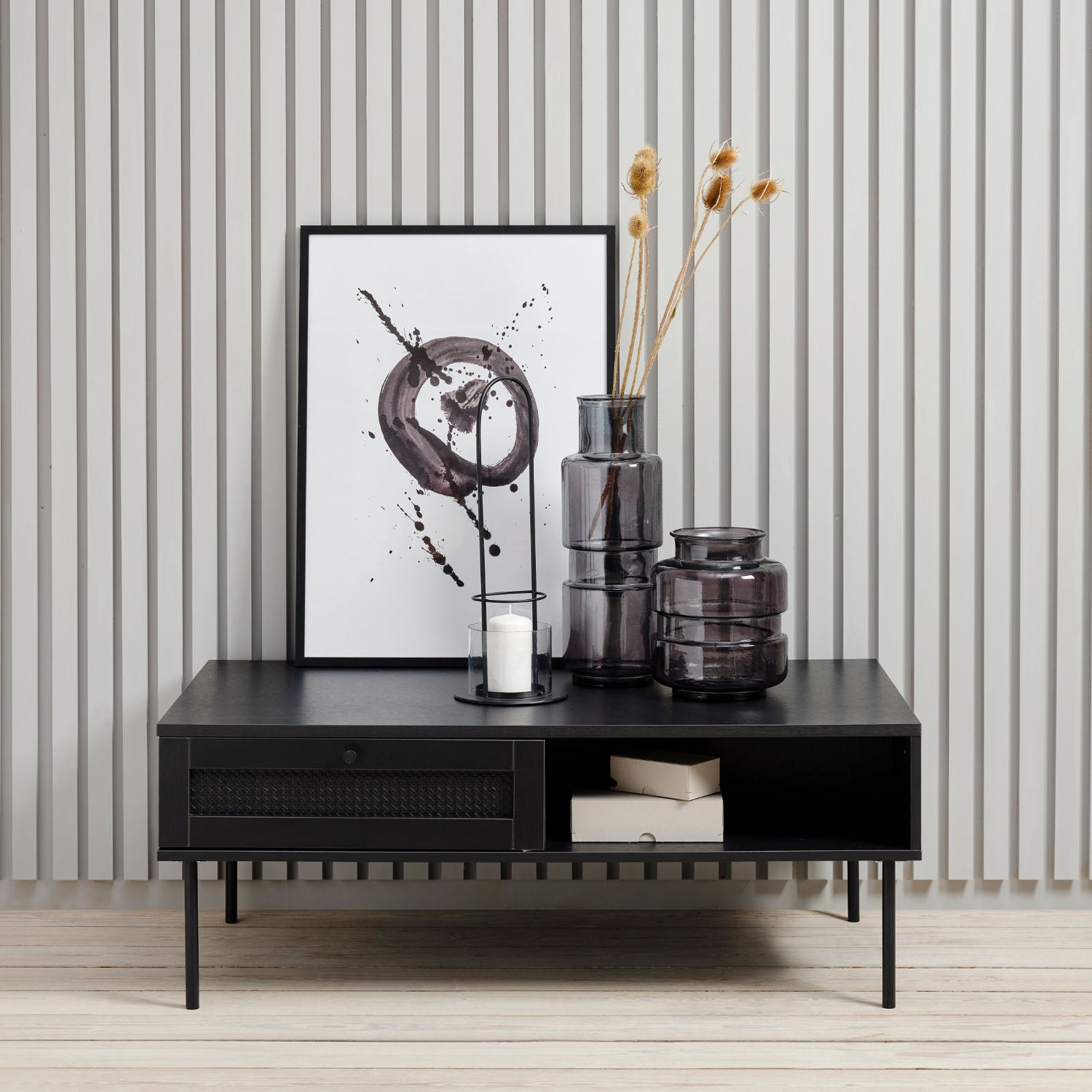 Kuvassa Pensacola-sohvapöytä, musta. Sohvapöydän molemminpuolisten laatikoiden etulevyissä on yksityiskohtana polyrottinki. Mustat metallijalat.