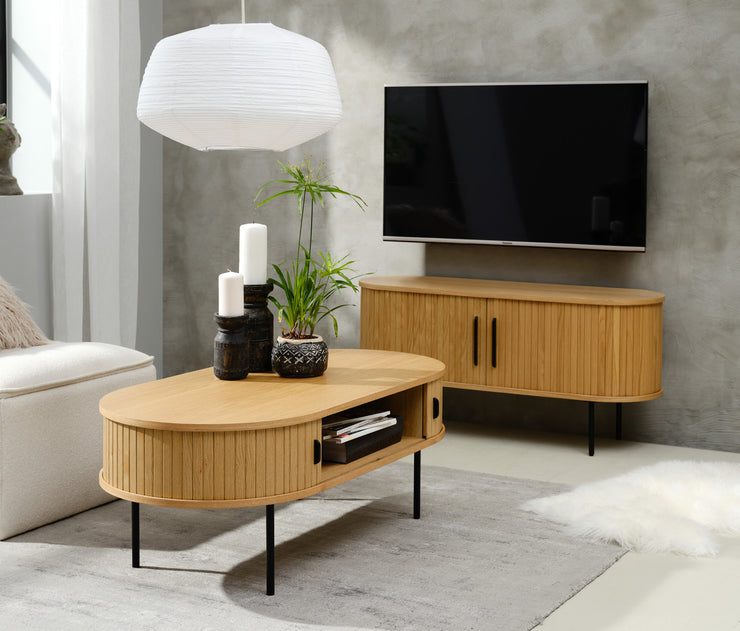Kuvassa on taustalla Nola-tv-taso 120 cm ja edustalla Nola-sohvapöytä. Ovaalinmuotoisissa tammenvärisissä tasoissa on mustat metalliset vetimet liukuovissa ja mustat säädettävät metallijalat.