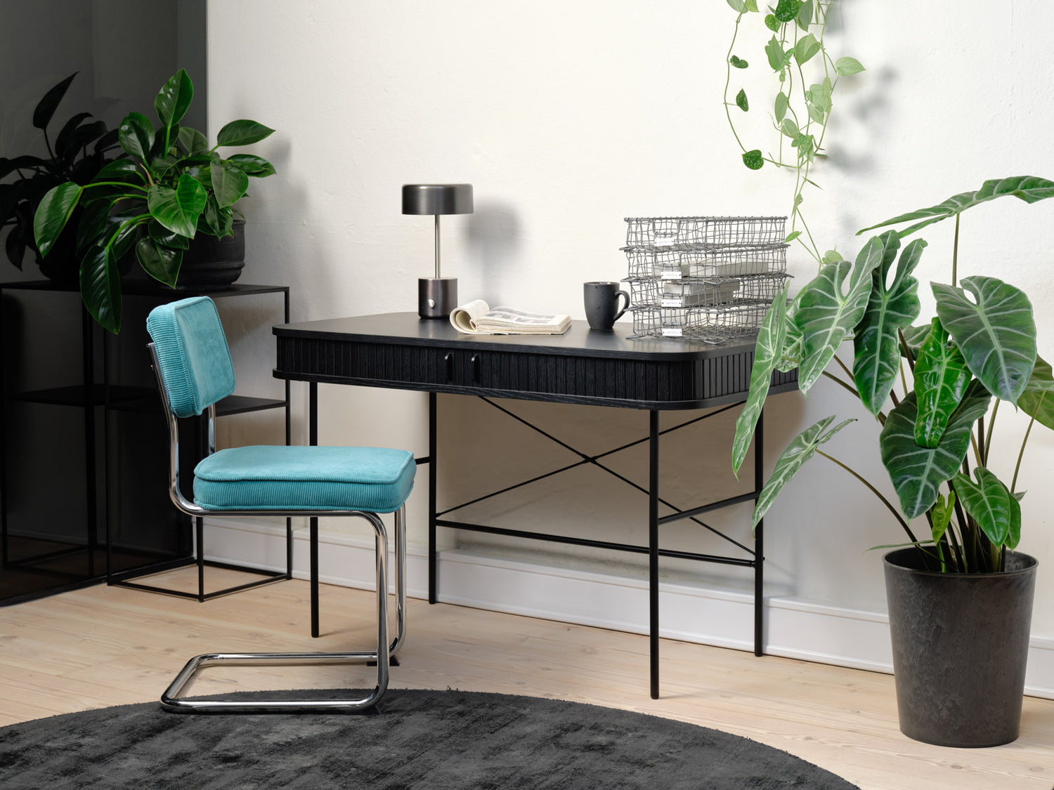 Kuvassa on Nola-työpöytä mustana. Sormipaneloiduissa liukuovissa on mustat metalliset vetimet ja mustat metallijalat ovat säädettävät.