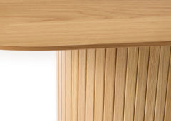 Lähikuvassa luonnonvärisen Nola-ruokapöydän kansilevyä ja jykevää jalkaa, johon panelointi on tuomassa ilmettä.