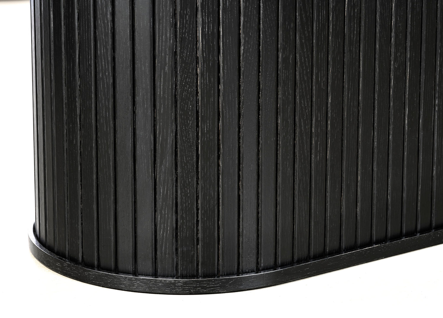 Lähikuvassa mustan Nola-ruokapöydän jykevä jalka, johon panelointi on tuomassa ilmettä.