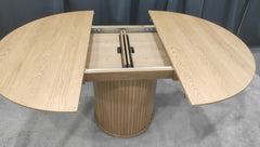 Jatkettava 120 cm Nola-ruokapöytä jatketaan keskeltä pöytää, jossa jatkopaloja säilytetään kannen alla.