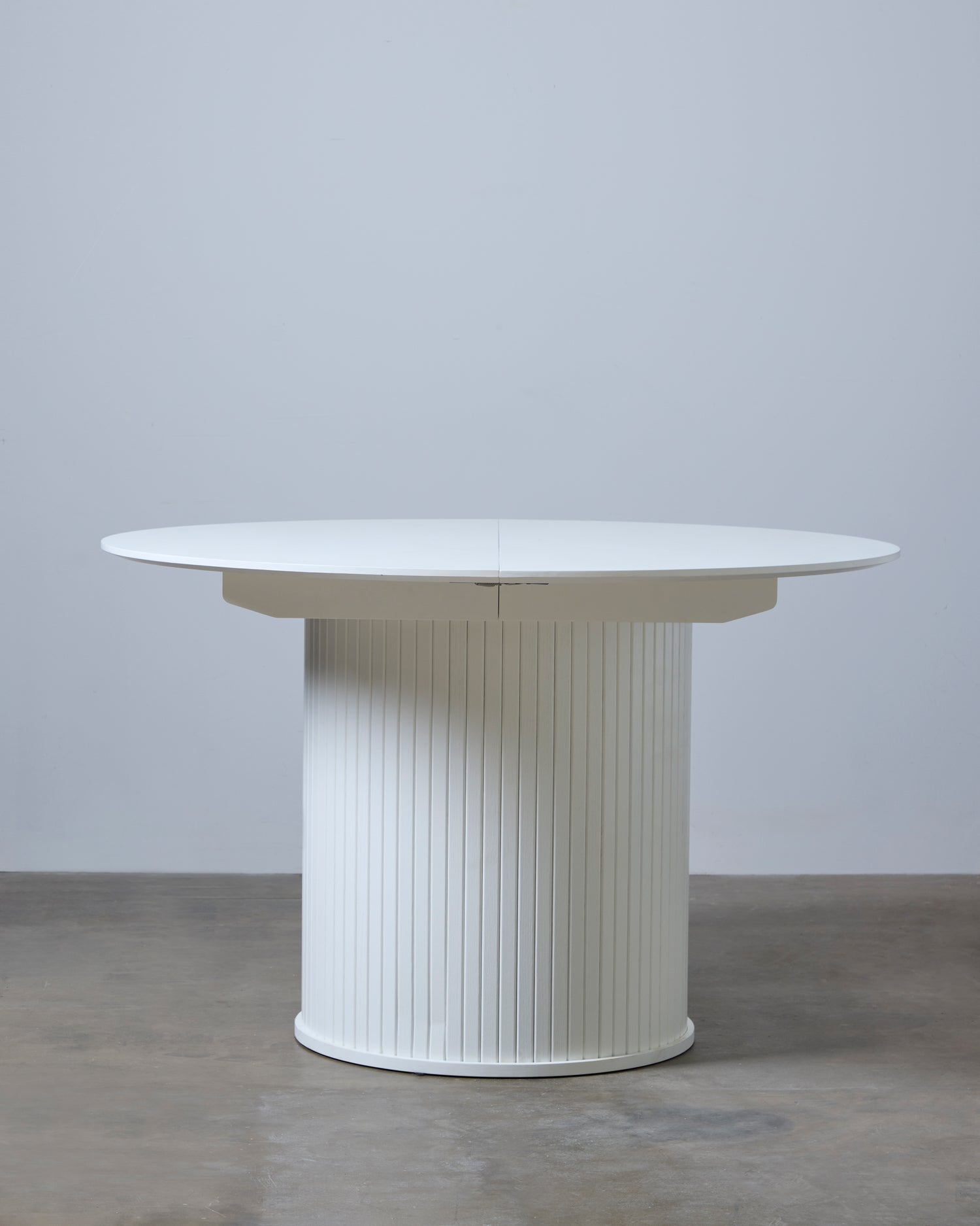 Valkoinen jatkettava Nola-ruokapöytä - pöytälevyn halkaisija 120 cm voidaan jatkaa 167 cm:n pöydän keskeltä saatavilla olevilla jatkoilla.