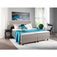 Kuvassa on beige Aallotar-jenkkisänkypaketti, johon sisältyvät profiloitu sijauspatja ja mustat puujalat. Kuvan Aalto-sängynpääty myydään erikseen.