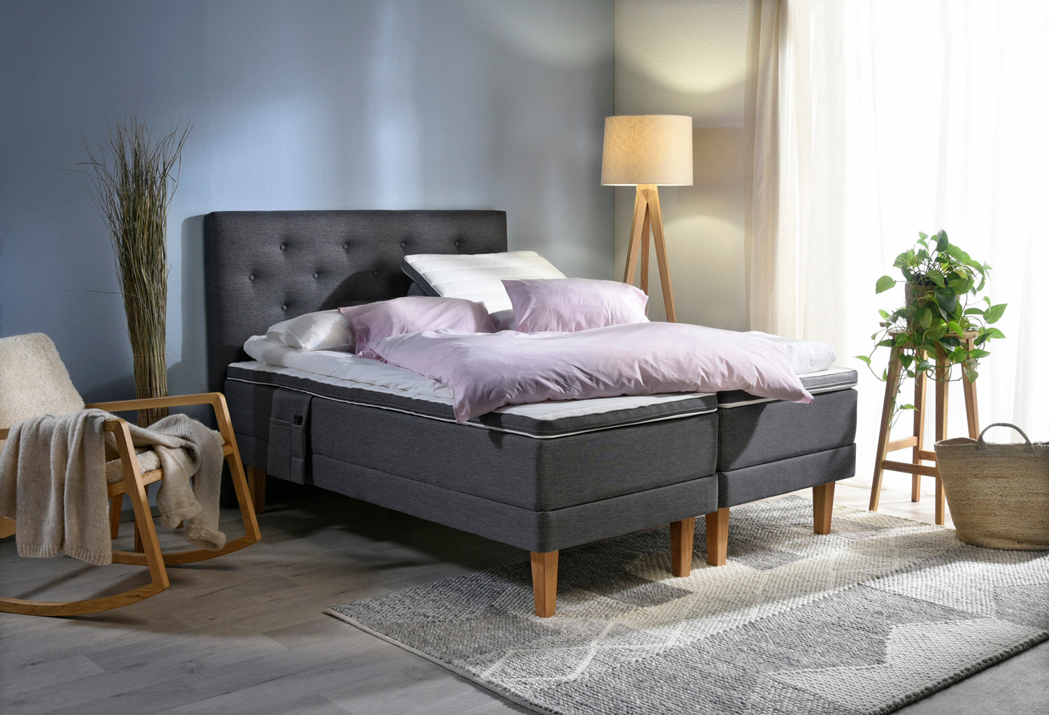 Antrasiitin värinen Aava-moottorisänky Royal-tammijaloilla ja profiloiduilla sijauspatjoilla. Kuvan sängynpääty ja tarviketasku myydään erikseen.