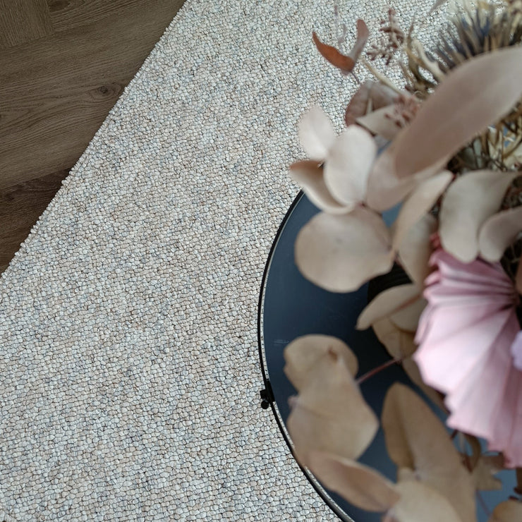 Kuvassa on beige-harmaa sileäpintainen Ahto-matto kuvattuna sohvapöydän alla.