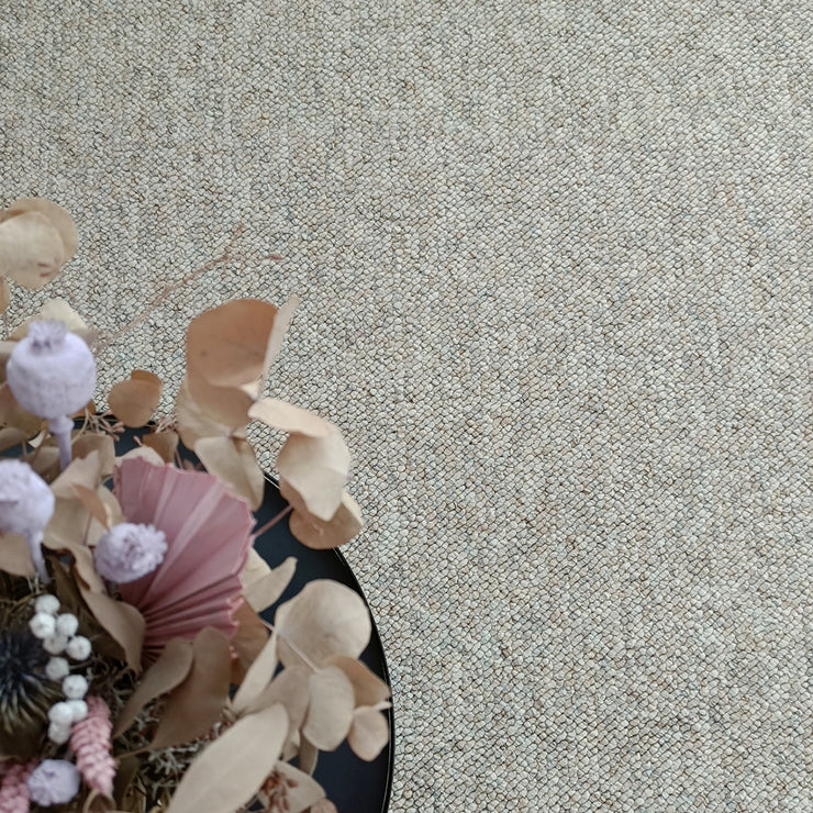 Kuvassa on beige-harmaa sileäpintainen Ahto-matto kuvattuna sohvapöydän alla.