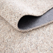 Lähikuvassa on beige-harmaa sileäpintainen Ahto-matto. Matto on taitettuna ja näkyvissä on myös sen pohjausta.