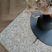 Kuvassa on beige-harmaa sileäpintainen Ahto-matto kuvattuna sohvapöydän alla.