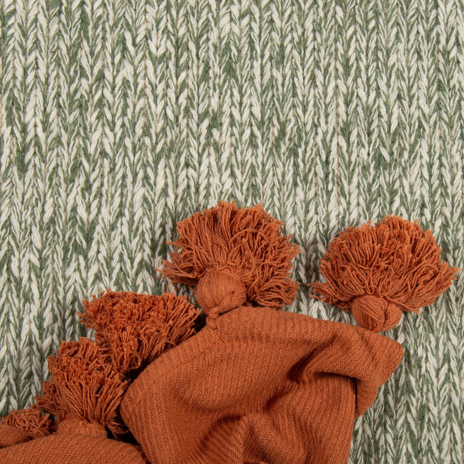 Kuvassa on vihreän Anna-villamaton kuosia ja terran värinen Sävel Tupsu -torkkupeitto.