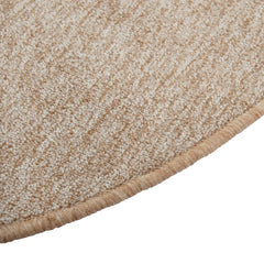 Lähikuvassa pyöreän Carina-maton reunausta - maton lämmin beige sävy, joka sisältää kevyttä meleerausta. 