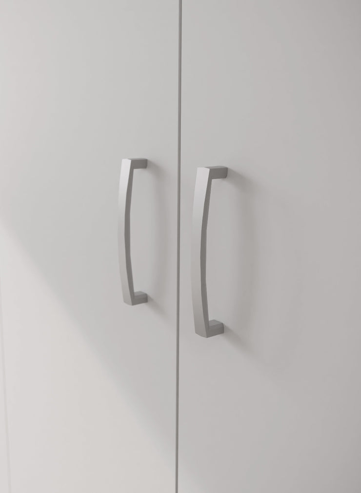 Lähikuvassa kokovalkoisen 3-ovisen Kira-komeron tuplaovikaapin hopeanharmaat vetimet.